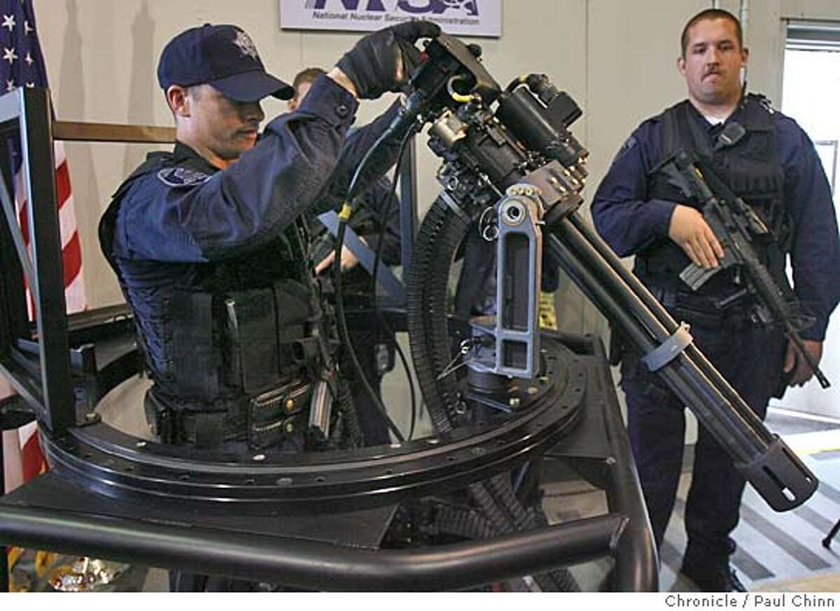 Lawrence Livermore police officer Andrew Graycar demonstrates how the new Dillon Aero gatling gun swivels as police officer Chris McKaskey (right) stands guard in Livermore, Calif. on 2/2/06. The state-of-the-art weapon, capable of firing up to 4,000 rounds per minute, will add to the arsenal already in place to protect the Lawrence Livermore National Laboratory. PAUL CHINN/The Chronicle
