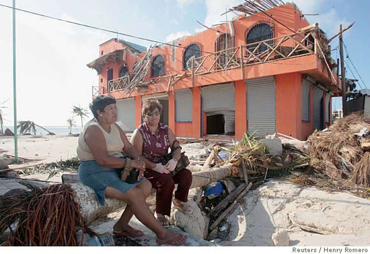Residents wait outside of their destroyed home after Hurricane Dean passed Majahual in the state of Quintana Roo, August 22, 2007. REUTERS/Henry Romero (MEXICO)