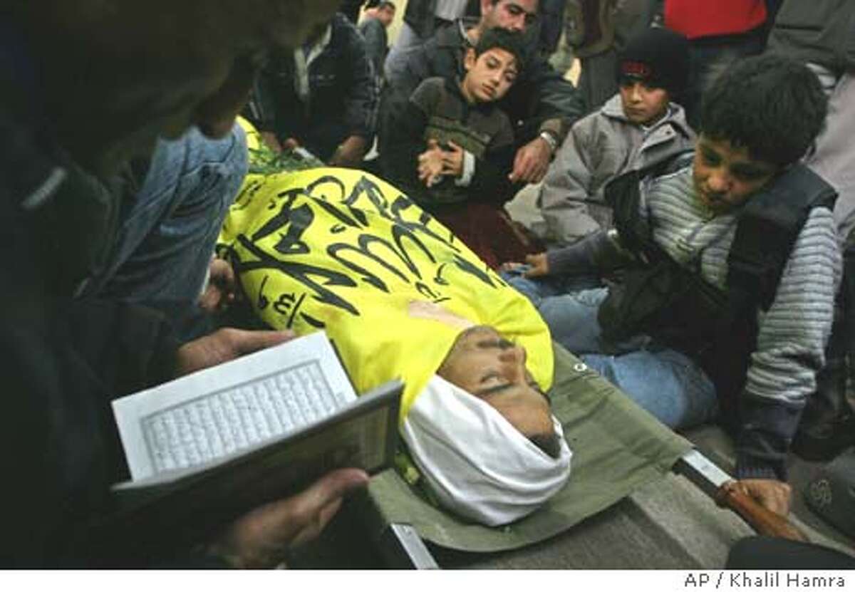 The sons of Ayed al-Najar look at the body of their father, a militant of a militia linked to Yasser Arafat's Fatah movement, during his funeral in a mosque in the southern Gaza Strip town of Rafah Tuesday, Dec. 23, 2003. He was one of the four gunmen killed Tuesday when about 40 Israeli tanks and armored vehicles entered the Rafah refugee camp on the Gaza-Egypt border. According to hospital officials, eight Palestinians, four civilians and four gunmen, were killed and 42 other people, including ninechildren, were wounded by Israeli gunfire.(AP Photo/Khalil Hamra)