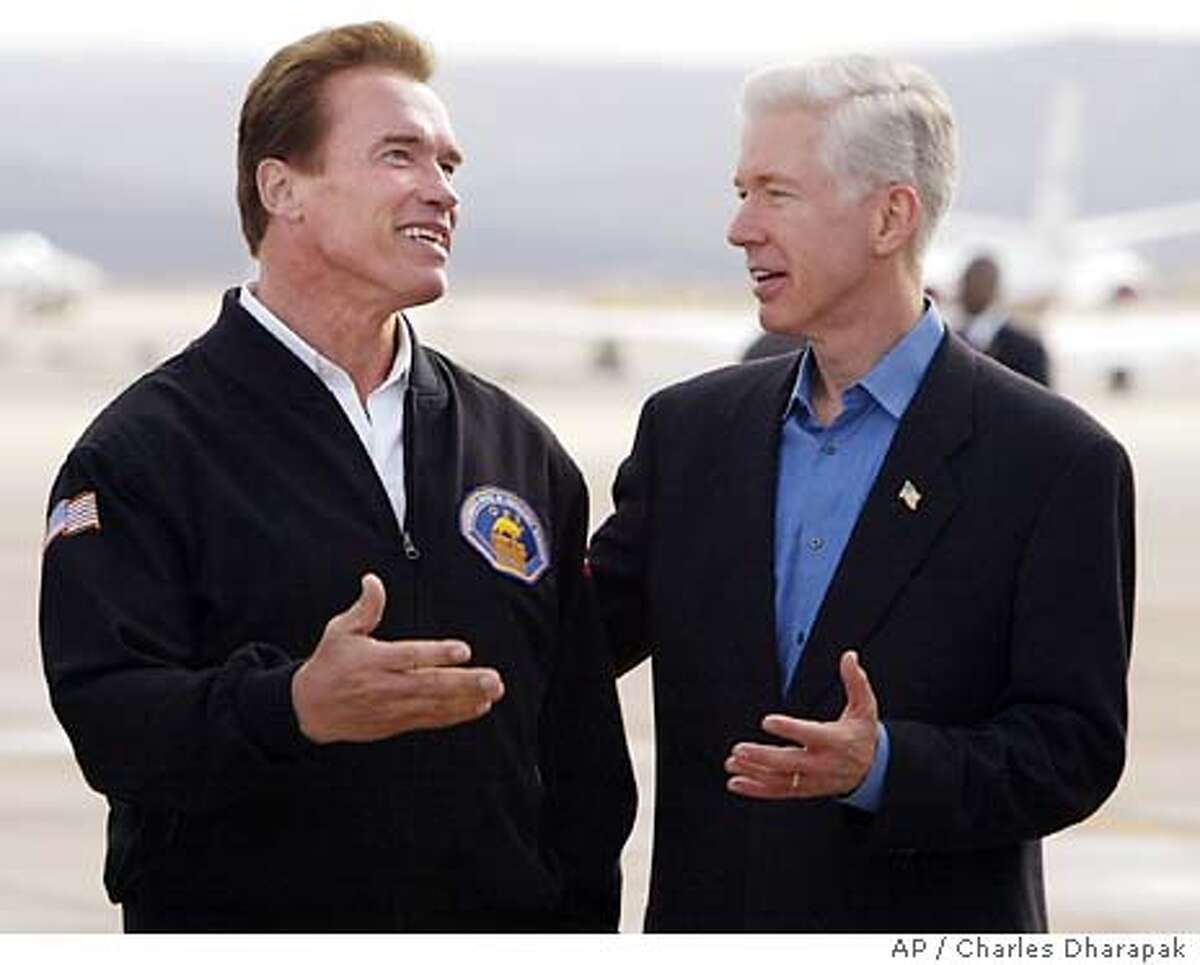 California Gov.-elect Arnold Schwarzenegger, left, chats with outgoing California Gov. Gray Davis as they wait for President Bush to disembark Air Force One at Marine Corps Air Station in Miramar, Calif., Tuesday, Nov. 4, 2003. (AP Photo/Charles Dharapak)