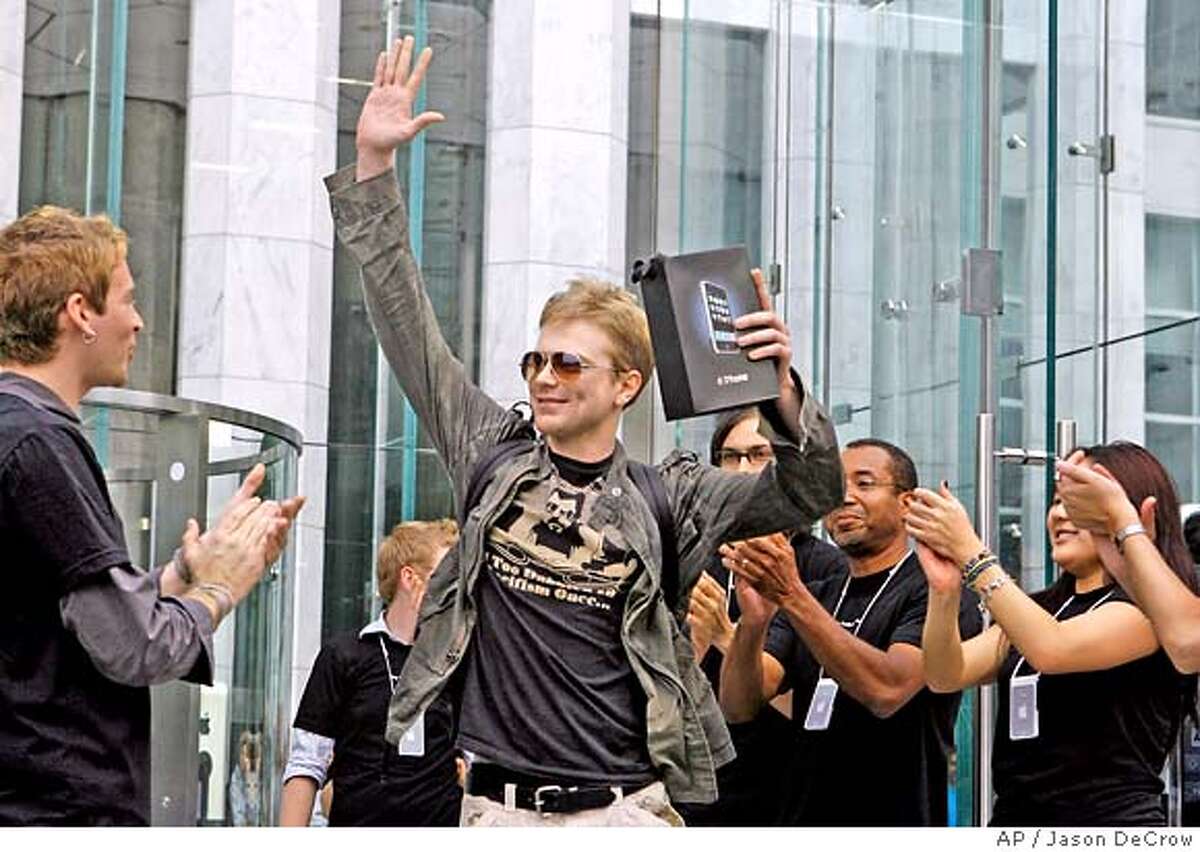 **FILE** Apple employees cheers as an excited customer leaves the Apple Store with his new iPhone in this June 29, 2007 file photo in New York. (AP Photo/Jason DeCrow, file)