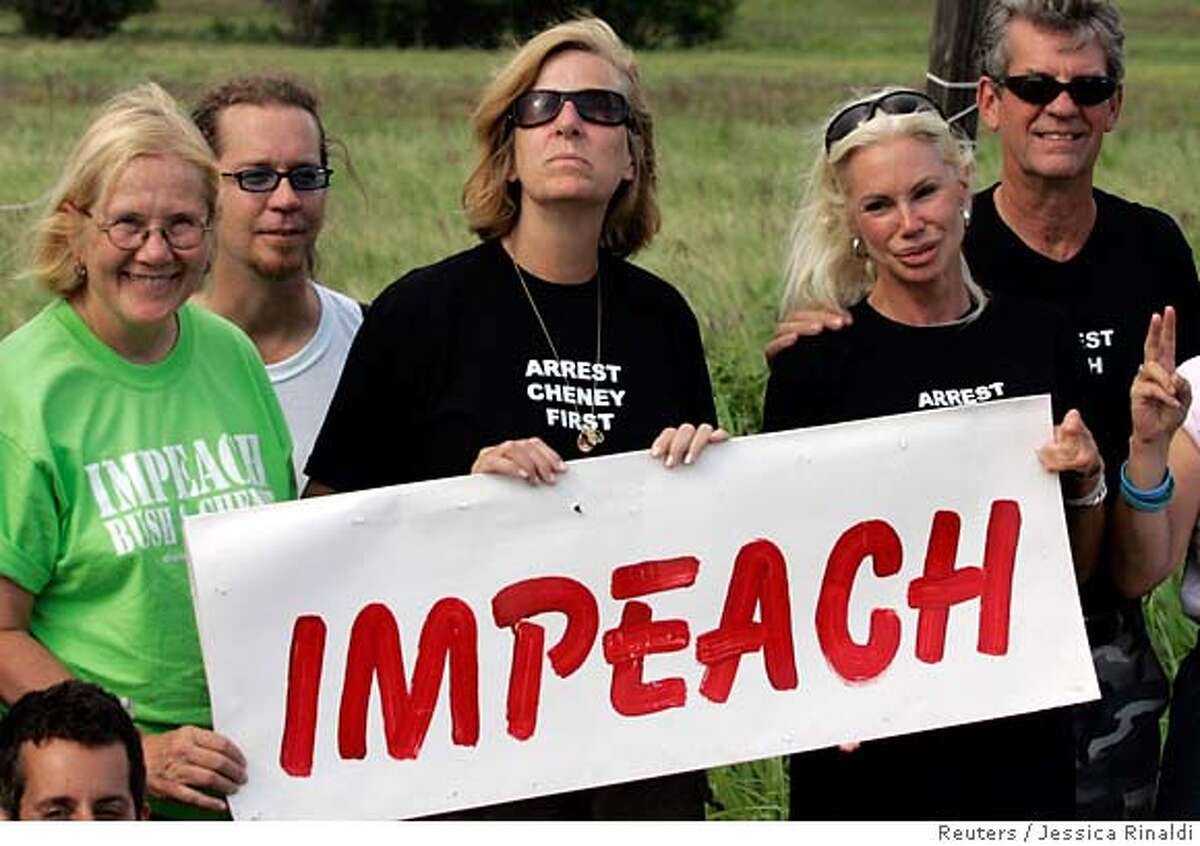Peace activist Cindy Sheehan (C) holds a sign with fellow activists as they pose for a picture at the site of her first protest near U.S. President George W. Bush's ranch in Crawford, Texas July 8, 2007. REUTERS/Jessica Rinaldi (UNITED STATES) 0