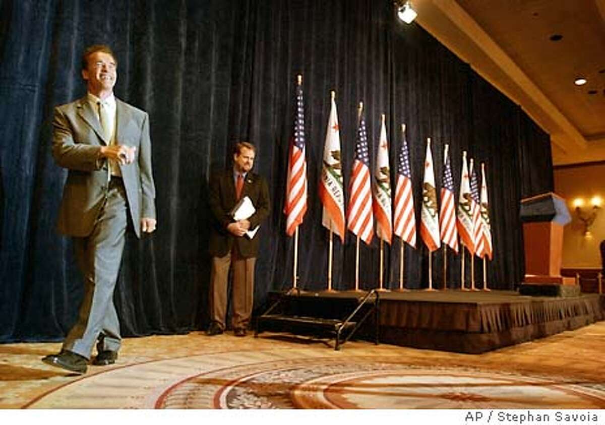Arnold Schwarzenegger, left, leaves the stage following a post-election press conference at a Los Angeles hotel, Wednesday, Oct. 8, 2003. (AP Photo/Stephan Savoia)