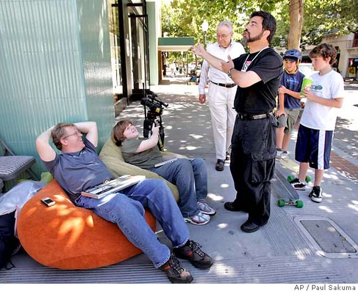 Apple store assistant manager Erez Saldinger, right, welcomes back Robert Scoble, left, and his son, Patrick, 13, center, after Apple told them earlier to leave during their wait in Palo Alto, Calif., Thursday, June 28, 2007 to purchase the new iPhone. The iPhone is planned to go on sale on Friday. (AP Photo/Paul Sakuma)