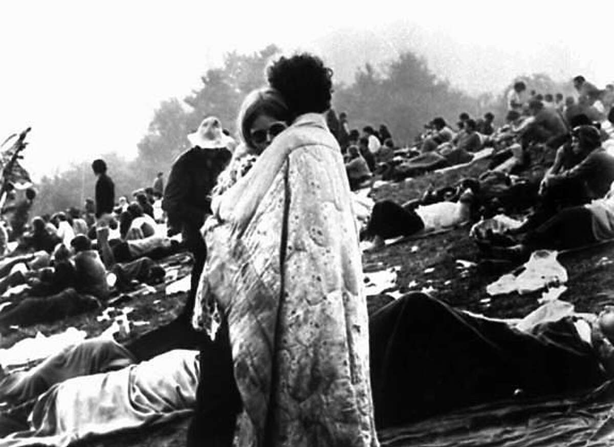ADV. FOR SUN., JUNE 24--FILE--A couple embrace on a muddy hillside in Bethel, N.Y. during the Woodstock Music and Art Fair in Aug., 1969. This image was featured in magazines, on posters and on the cover of the Woodstock concert album. (AP Photo/Warner Bros.-files) B/W ONLY. ADV. FOR SUN., JULY 24