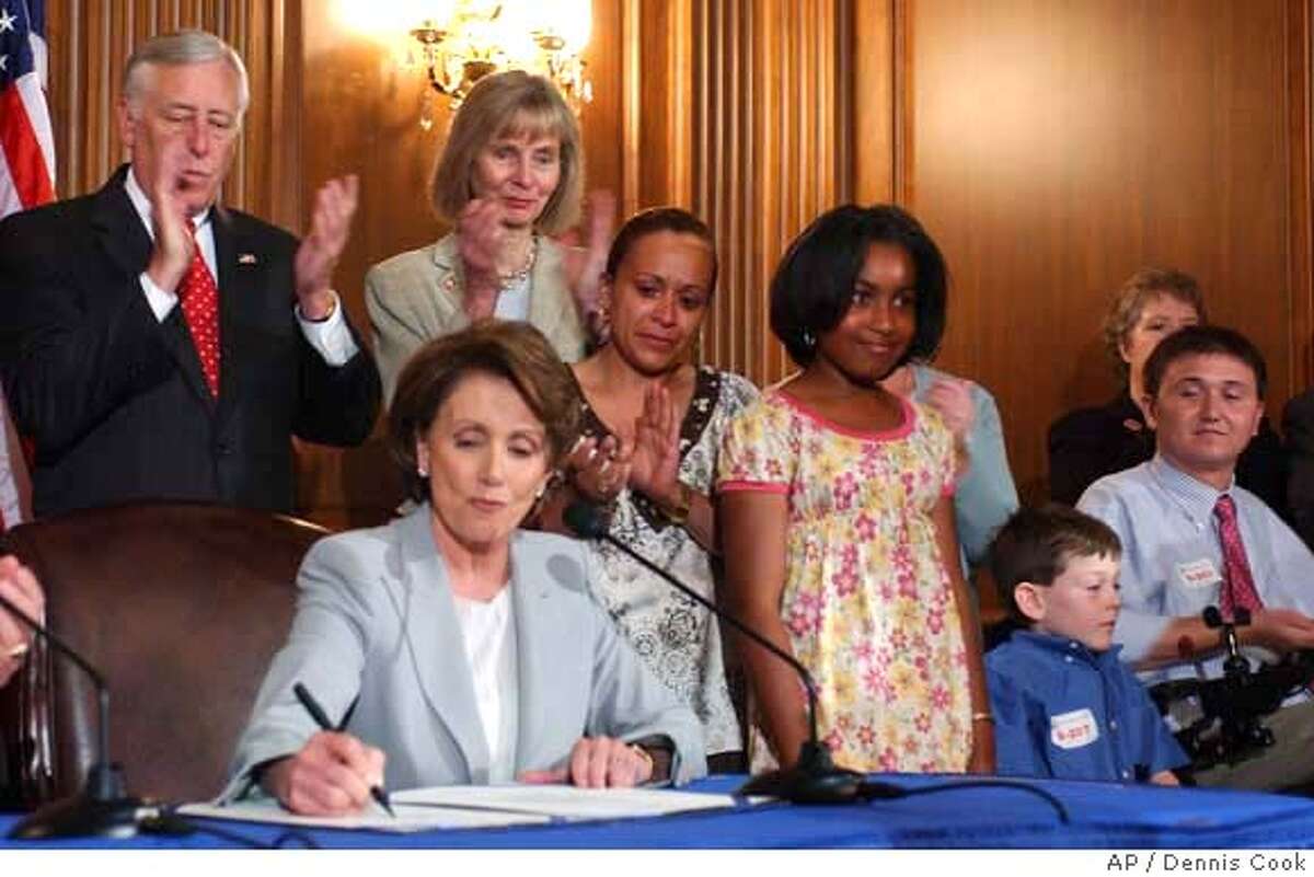 House Speaker Nancy Pelosi of Calif., seated, signs a stem cell research bill on Capitol Hill in Washington, Thursday, June 7, 2007. House Majority Leader Steny Hoyer of Md., standing, left, Rep. Lois Capps, D-Calif., standing, second from left, and others, look on. (AP Photo/Dennis Cook)