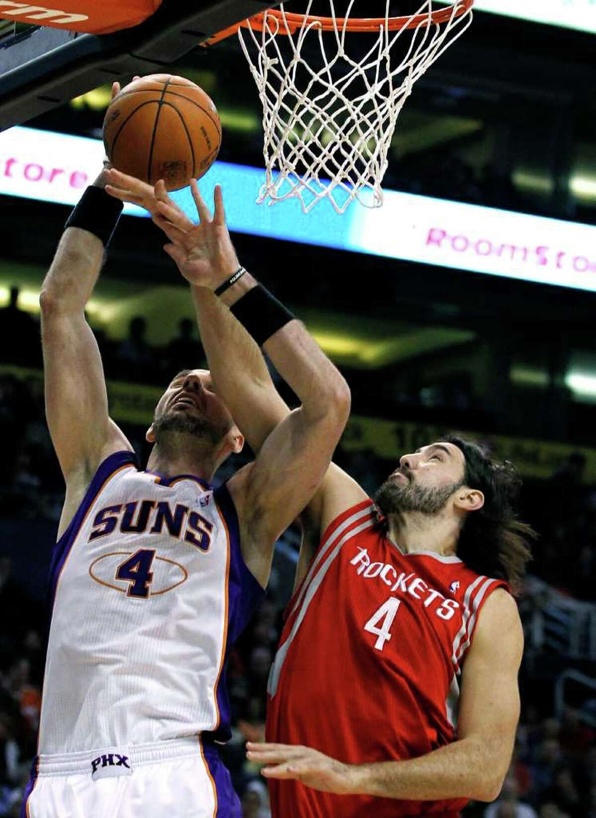 Phoenix Suns' Marcin Gortat, left, of Poland, gets fouled by Houston Rockets' Luis Scola, of Argentina, as he goes up for a shot during the first quarter in an NBA basketball game, Sunday, March 18, 2012, in Phoenix. (AP Photo/Ross D. Franklin)