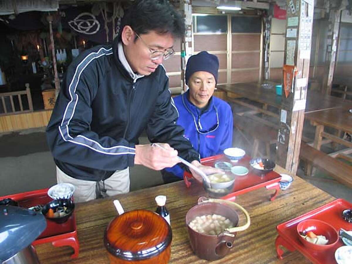 TRAVEL KII -- Nobohiro Ashihara of the local prefecture office serves soup to Jim Sano of Geographic Expeditions in the shukobo -- temple lodge -- atop Mount Omine