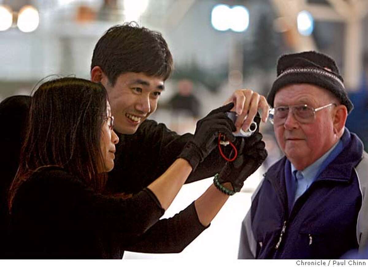 Rosa Cheung and Akira Kondo snap a photographic memento with longtime skating coach Tony Howard (right) at Berkeley Iceland in Berkeley, Calif. on Wednesday, March 28, 2007. Howard has been a coach at Iceland for 55 years. The East Bay landmark is scheduled to shut its doors for good on Saturday after 66 years unless a last minute effort by diehard skaters can scrape enough money together to buy the facility and run it as a nonprofit. PAUL CHINN/The Chronicle **Rosa Cheung, Akira Kondo, Tony Howard