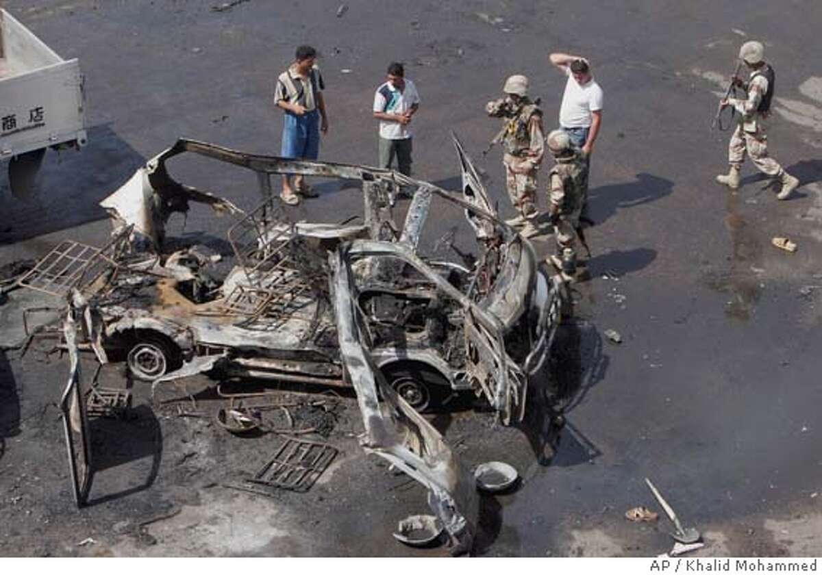 Iraqis stand around a minibus that was blown up by a suicide bomber in Baghdad, Iraq, Friday, Sept. 23 2005. A suicide bomber riding on the small public bus set off hidden explosives in a bustling open-air bus terminal Friday, the Muslim day of worship, killing at least five people and wounding eight, police said. (AP Photo/Khalid Mohammed) Ran on: 09-24-2005 Iraqis stand around a minibus that was blown up by a suicide bomber in central Baghdad.
