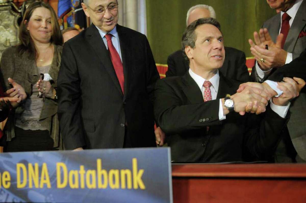 Governor Andrew Cuomo, right, shakes hands with a legislator as Ann M., left, from Queens, NY, and Assembly Speaker Sheldon Silver, center, look on after the Governor signed the DNA expansion bill on Monday, March 19, 2012 at the Capitol in Albany, N.Y. Ann M. has been an advocated for the expansion of DNA collection for years. Ann M. began her work to get the expansion of DNA collection shortly after her daughter's rape in her own bedroom by a man who broke into their home some years ago. (Paul Buckowski / Times Union)