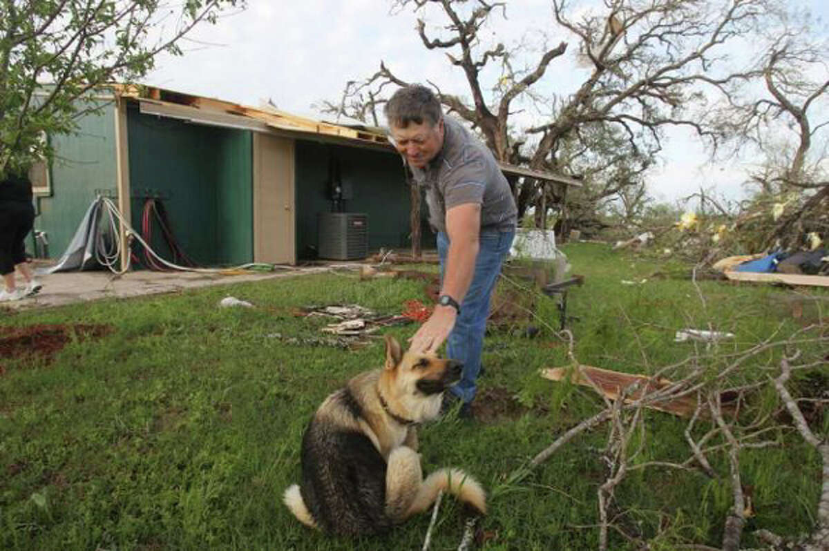 James Littleton pets his dog Shadow after looking over the damage that took place at his home Monday night March 19, 2012 on private road 6744 between Lytle and Natalia, Texas. Littleton was at home with his wife Donna Littleton when they said they heard loud noises outside and took cover in their bath tub for shelter. Speaking about his dog, Littleton said, "she's traumatized." (John Davenport / San Antonio Express-News)