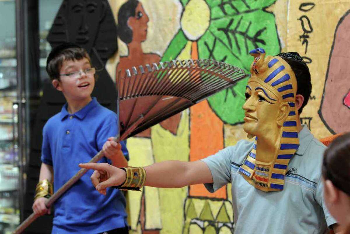 Eli Kochman of Albany, 12, dressed as aPharaoh, right, is cooled by a makeshift fan, a rake, by Amiel Ehrlich, 12 as they and fellow students from the Maimonides Hebrew Day School re-enact the exodus of the Jews from Egypt. The students from Albany then saw a demonstration of matzo making at Price Chopper in Colonie. A member of the family who runs Streit's, a company from New York City that has made matzo since 1925, was in attendance. (Philip Kamrass / Times Union )