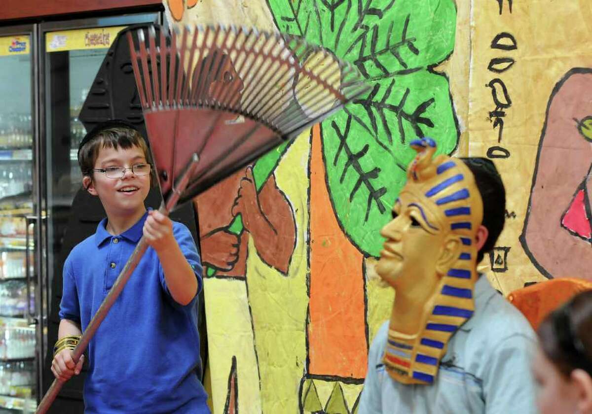 Eli Kochman of Albany, 12, dressed as aPharaoh, right, is cooled by a makeshift fan, a rake, by Amiel Ehrlich, 12 as they and fellow students from the Maimonides Hebrew Day School re-enact the exodus of the Jews from Egypt. The students from Albany then saw a demonstration of matzo making at Price Chopper in Colonie. A member of the family who runs Streit's, a company from New York City that has made matzo since 1925, was in attendance. (Philip Kamrass / Times Union )