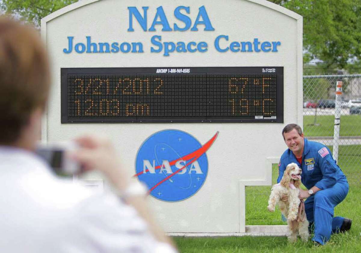 NASA Astronaut Mike Foreman poses for photos with Jenny, a dog from Cocker Spaniel Rescue of East Texas, at Johnson Space Center, Wednesday, March 21, 2012, in Houston.