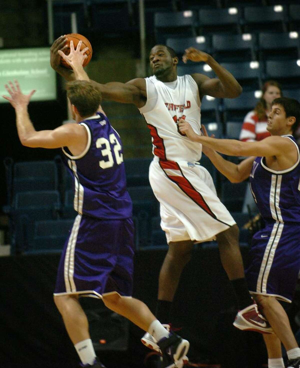 Fairfield's Anthony Johnson grabs a rebound between two Stonehill defenders during a recent game at the Arena at Harbor Yard in Bridgeport.