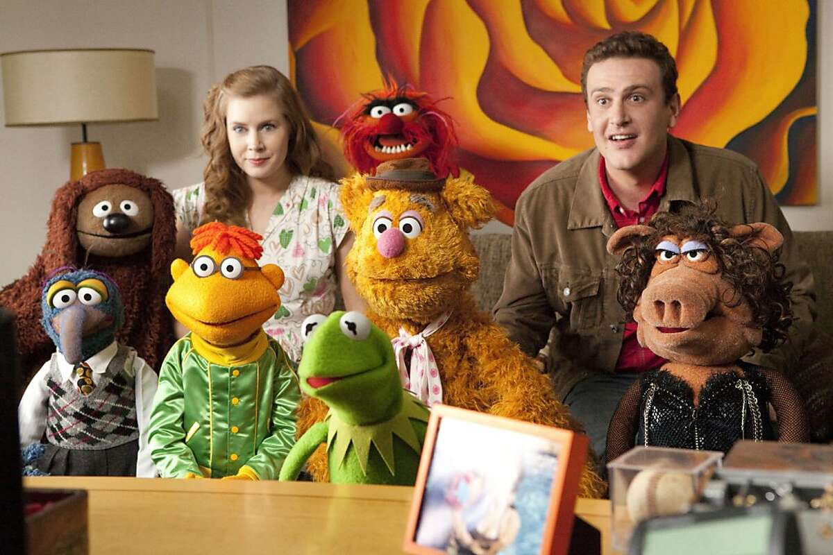 In this film publicity image released by Disney, Amy Adams, left, and Jason Segel are shown with the muppet characters in a scene from "The Muppets." (AP Photo/Disney Enterprises, Patrick Wymore)