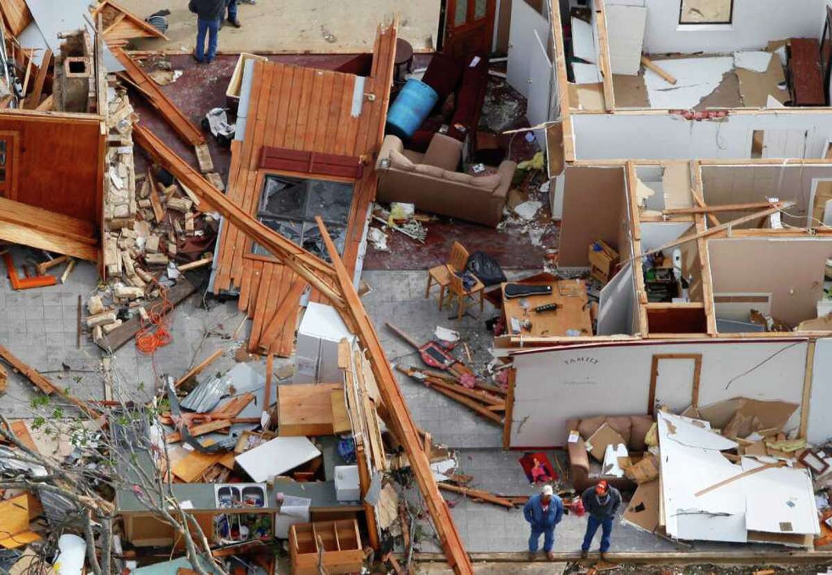 Two men stand (bottom center of image) in the remains of a house damaged from an overnight tornado in the Devine area, as seen in this Tuesday March 20, 2012 aerial image.