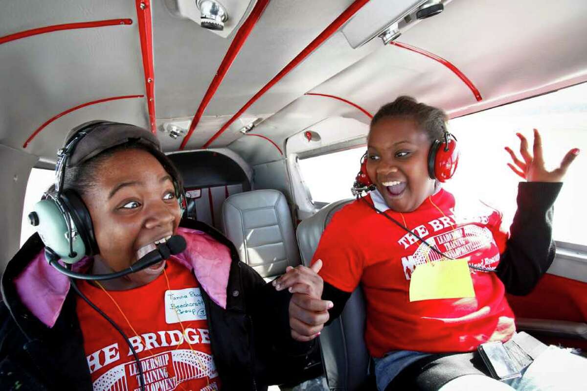 Tianna Rhodes, 11, and Tylandria Harrison, 11, react to what is their first flight ever, as the Piper Cherokee Six aircraft flown by Chris Prause takes off from the runway at the Houston Southwest Airport, Saturday, Feb. 12, 2011, in Rosharon. Forty kids from the troubled Haverstock apartment complex were bussed to the Texas Taildraggers flight school where they took a 20 minute ride in the sky in the hopes they see life beyond the gates of their home.
