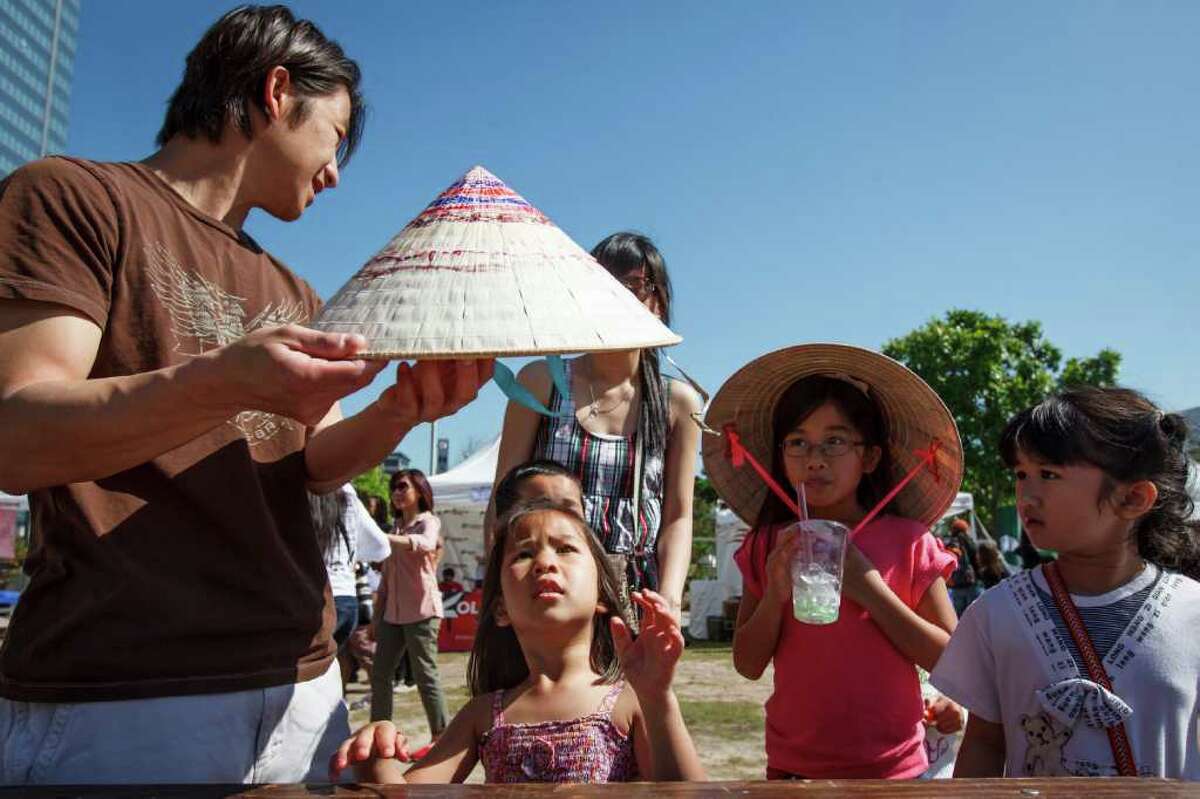 Core La holds a straw hat for his daughter, Ellie, 4, as his other daughter Sydney, 7, looks on during the Hope Initiative's 2012 Vietnamese Festival in honor of Vua Hùng (Hùng kings), founders of Vietnam, at Discovery Green, Saturday, March 24, 2012, in Houston.