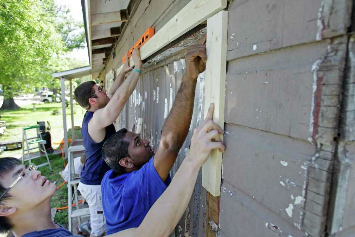 Second Baptist Church volunteers Joey Jurkash, rear, Stanley Ninan, center, and Felix Lincoln, foreground, cooperate to replace trim Saturday on a home on Keystone during the Rebuilding Together Houston project.