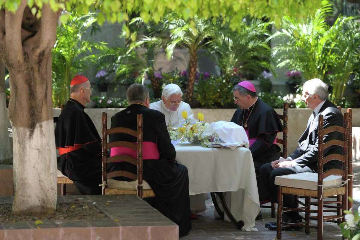In this picture made available by the Vatican newspaper Osservatore Romano, Pope Benedict XVI, center, sits with prelates in the yard of Colegio de Miraflores in Leon, Mexico, Saturday March 24, 2012. Benedict arrived in Mexico Friday afternoon, a decade after the late Pope John Paul II's last visit, and will travel to Cuba on Monday.