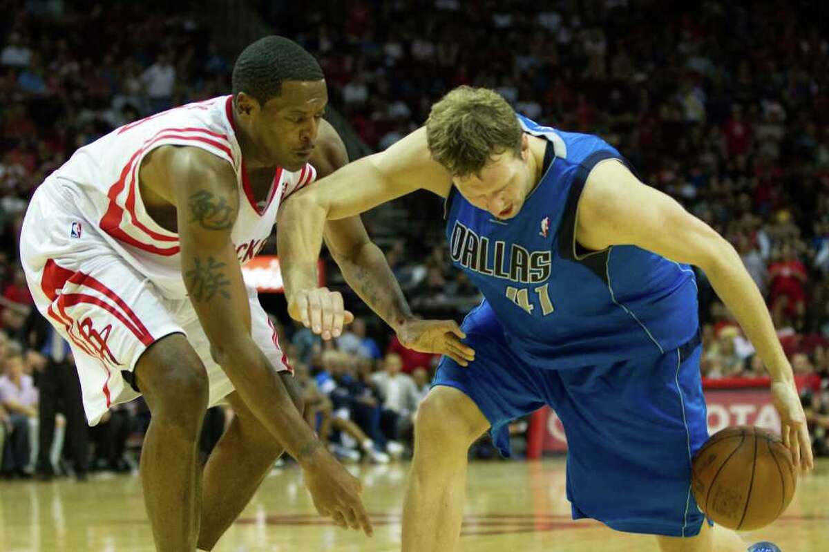 Houston Rockets center Marcus Camby (29) tries to knock the ball away from Dallas Mavericks power forward Dirk Nowitzki (41) during the overtime of an NBA basketball game at Toyota Center on Saturday, March 24, 2012, in Houston. The Mavericks won the game 101-99 in overtime.