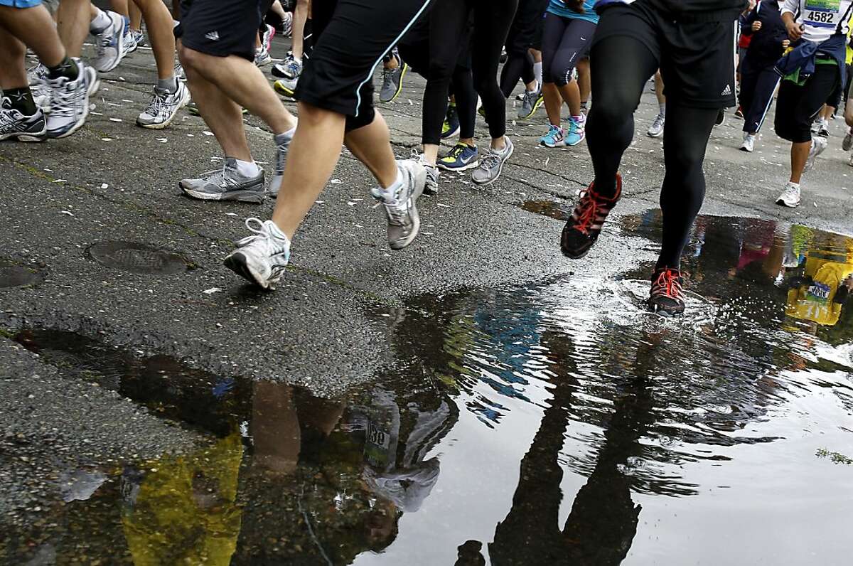 Rain puddles got in the way of some runners of the half marathon as they made their way up 19th Street. The Oakland Running Festival avoided the rain at the start of the marathon Sunday March 25, 2012.