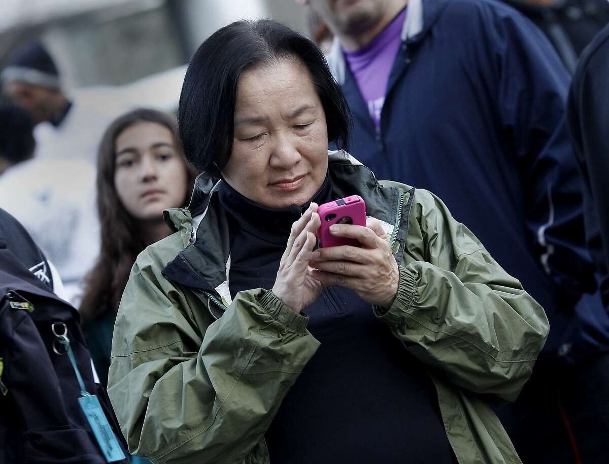 Oakland Mayor Jean Quan checked the weather on her smart phone before the start of the marathon. The Oakland Running Festival avoided the rain at the start of the marathon Sunday March 25, 2012.
