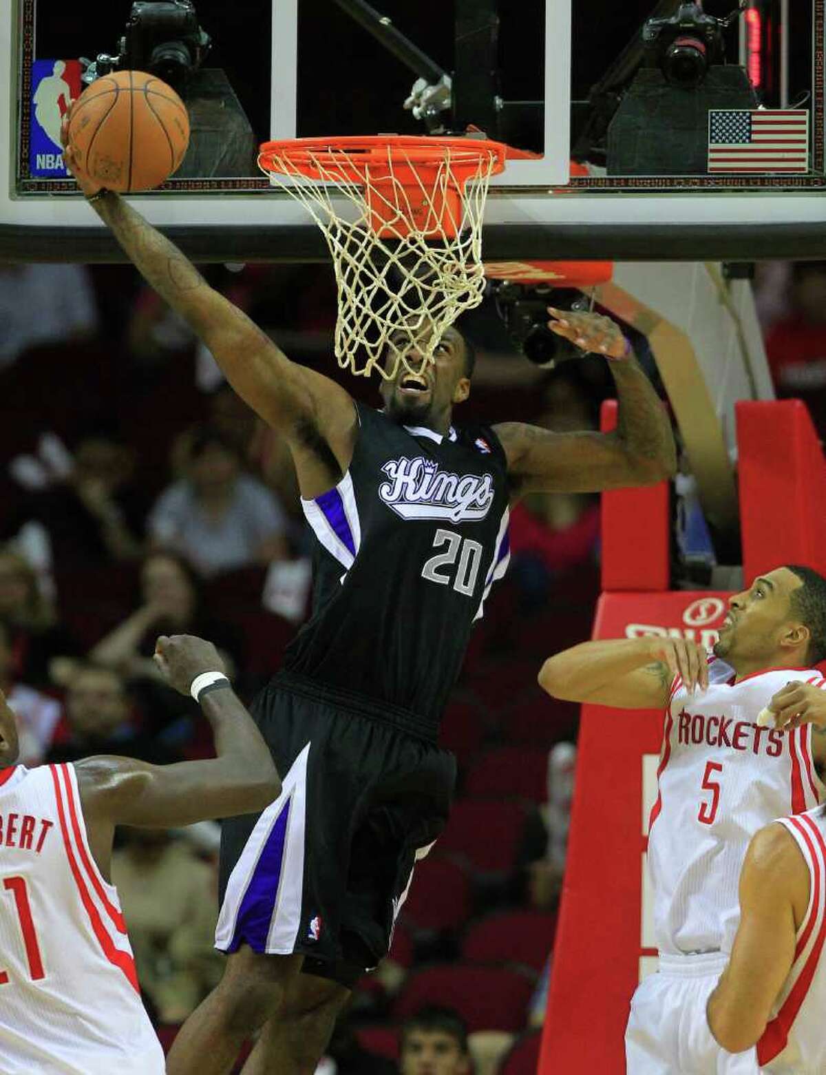 Sacramento Kings small forward Donte Greene (20) dunks the ball over Houston Rockets center Samuel Dalembert (21) and shooting guard Courtney Lee (5) during the first half of a basketball game at the Toyota Center Monday, March 26, 2012, in Houston.