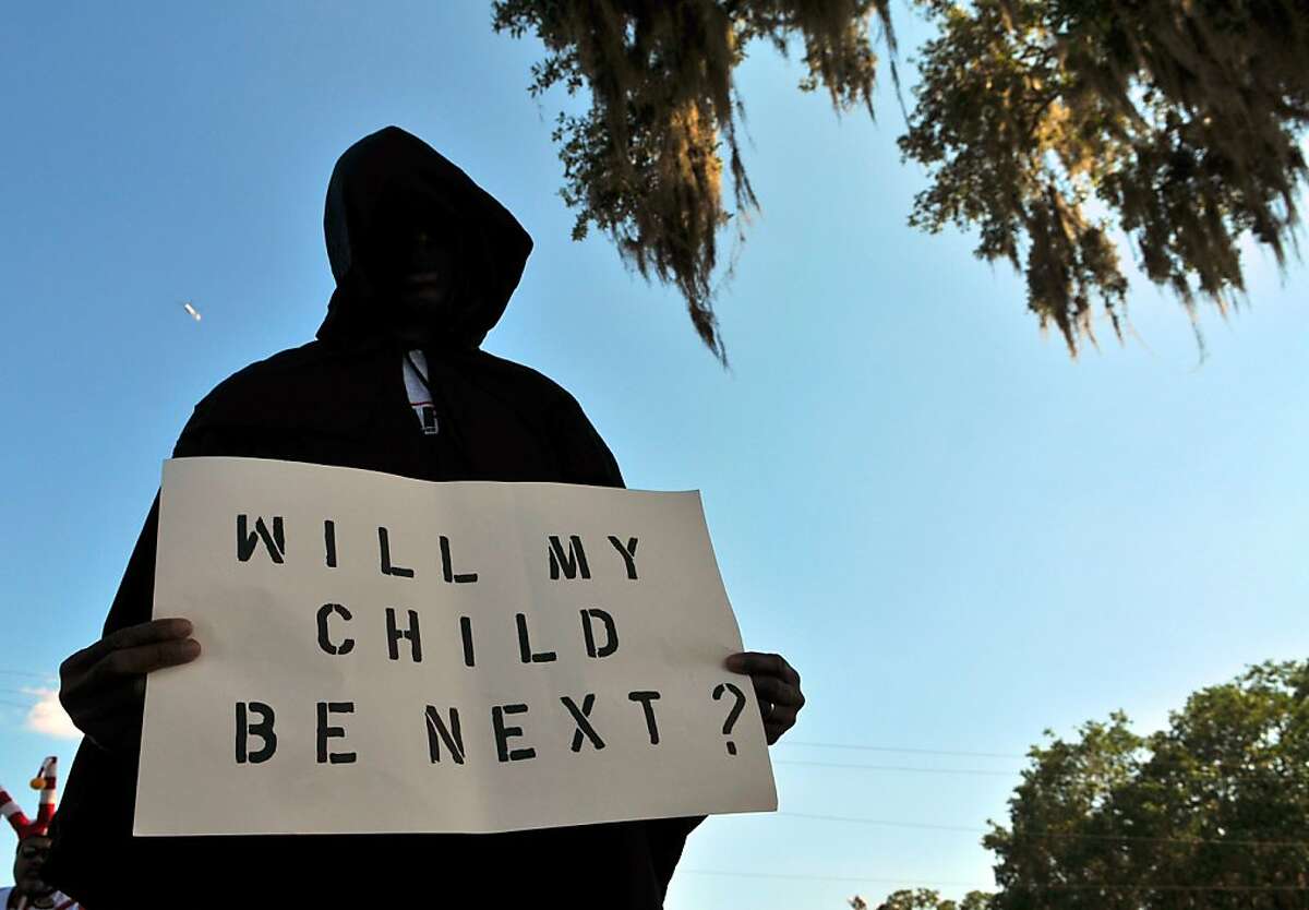 SANFORD, FL- MARCH 26: A man dressed in a hood holds up a sign saying "Will My Child Be Next?", during a protest march just prior to a town hall meeting March 26, 2012 in Sanford, Florida. The teenager's family addressed the town hall meeting along with Rev. Al Sharpton. Martin was killed by George Michael Zimmerman while on neighborhood watch patrol in the city. (Photo by Roberto Gonzalez/Getty Images)