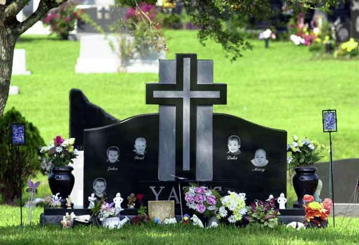 Flowers, angels and small toys sit at the base of the headstone of the five slain Yates children, Noah, John, Paul, Luke and Mary, at a Houston cemetery Tuesday, June 18, 2002, nearly one year after they were drowned by their mother, Andrea Yates. (AP Photo/Pat Sullivan)