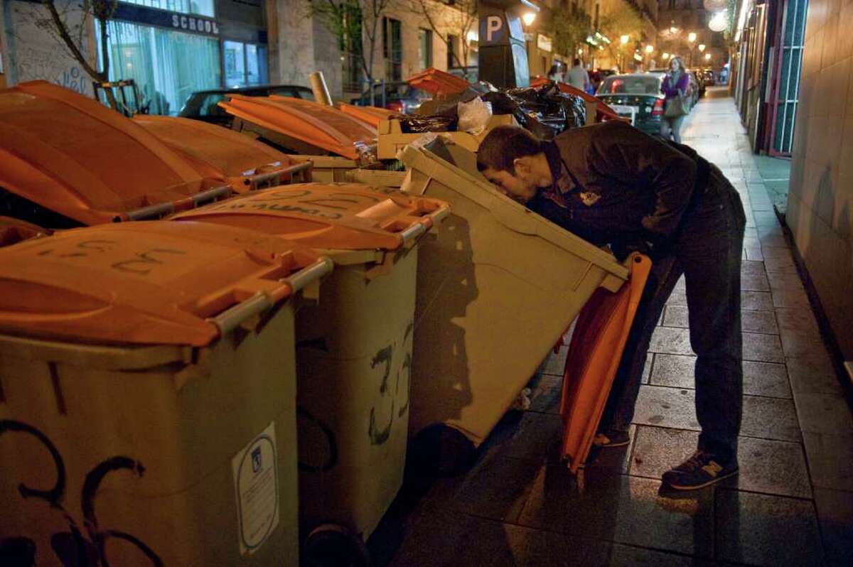 A man looks for food in a trash bin in Madrid Tuesday, March 27, 2012. Many stores throw out food when they close every night and people often gather to look though the garbage bins. A one-day trade union-sponsored general strike will take place Thursday March 29, 2012 to protest austerity measures permitting less costly worker hirings and firings. Prime Minister Mariano Rajoy has only given hints about the next round of fiscal pain he'll invoke for Spain, battered with highest unemployment rate among the nations that use the euro as it lurches toward its second recession in three years.( AP Photo/Pedro Acosta)