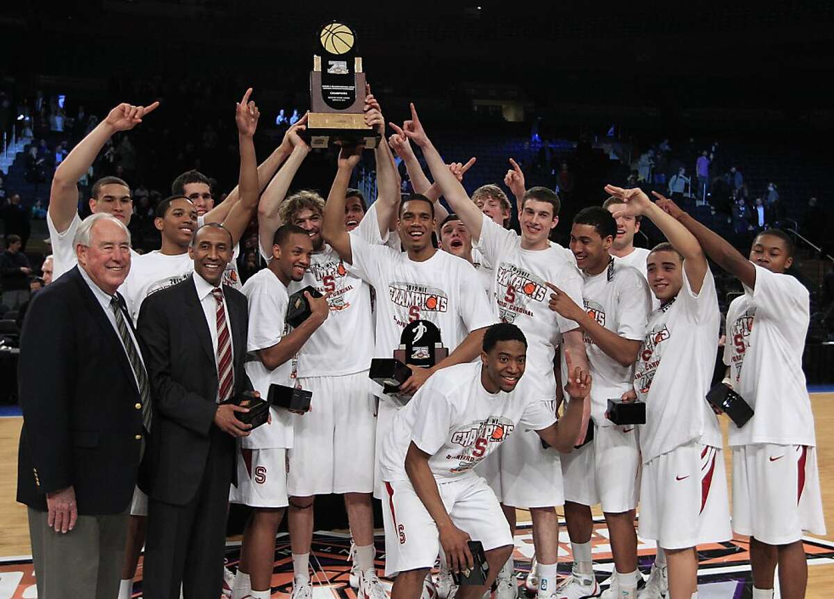 Stanford head coach Johnny Dawkins, second from front left, and Aaron Bright, second from front right, pose for photographs with teammates and the tournament trophy after the NIT college basketball tournament final against Minnesota Thursday, March 29, 2012, in New York. Stanford won the game 75-51. (AP Photo/Frank Franklin II)