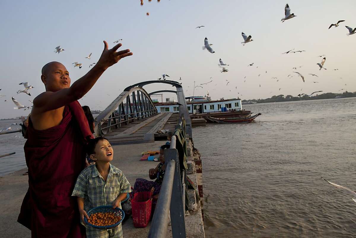 A Burmese monk and his son feed the seagulls on a jetty along the Yangon river March 29, in Yangon, Myanmar.