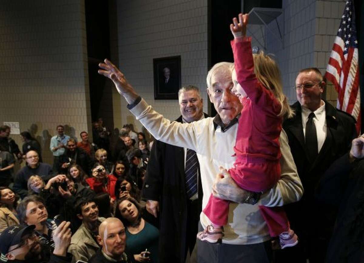 Republican presidential candidate Ron Paul shows 2-year-old Piper DeYoung how to wave to the crowd during a campaign stop Saturday, Feb. 4, 2012, in Rochester, Minn. (Charles Rex Arbogast / The Associated Press)