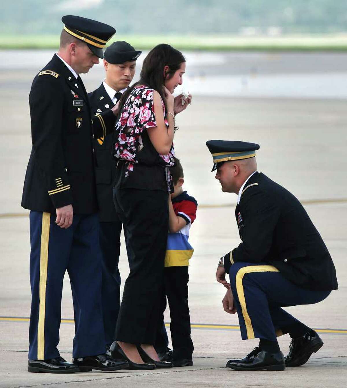 An unidentified U.S. Army officer, right, consoles Dean Ray, 5, hiding behind his mother Shannon Ray's leg, after the remains of Army 1st Lt. Clovis T. Ray, Dean's father, arrived at the Kelly Field Flightline. Ray died March 15th in the Kunar province in Afghanistan. Friday, March 30, 2012. The memorial service for Ray is Saturday at the Live Oak County Coliseum between Three Rivers and George West. Three Rivers Mayor James Liska recalls Army Lt. Clovis Ray as a leader even when they both played on a high school football team that made the state playoffs two years in a row. "He was the guy that it didn't matter who you were, what walk of life you came from, he was just your friend," said Liska. Ray was elected class favorite two years in a row while becoming an honors student. "Everybody just loved him, " Liska said. Bob Owen/San Antonio Express-News.