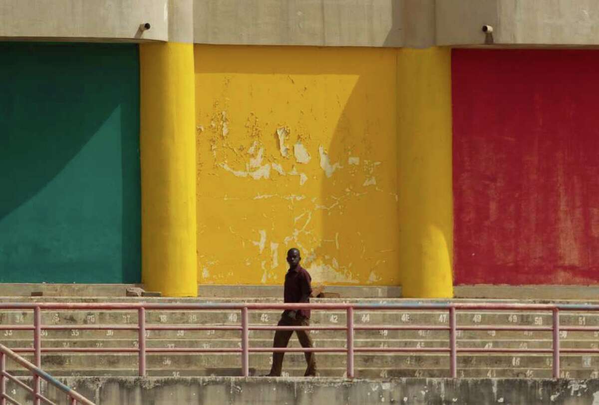 A man walks in front of a wall painted in the colors of the Malian flag, during a rally in support of the ruling military junta attended by roughly one thousand people in a stadium with a capacity of 50,000, in Bamako, Mali Saturday, March 31, 2012. The March 26 stadium is named in commemoration of the date in 1991 when dictator Moussa Traore was overthrown, paving the way for establishment of a democracy which lasted 21 years until mutinous soldiers took power in a coup nine days ago. (AP Photo/Rebecca Blackwell)