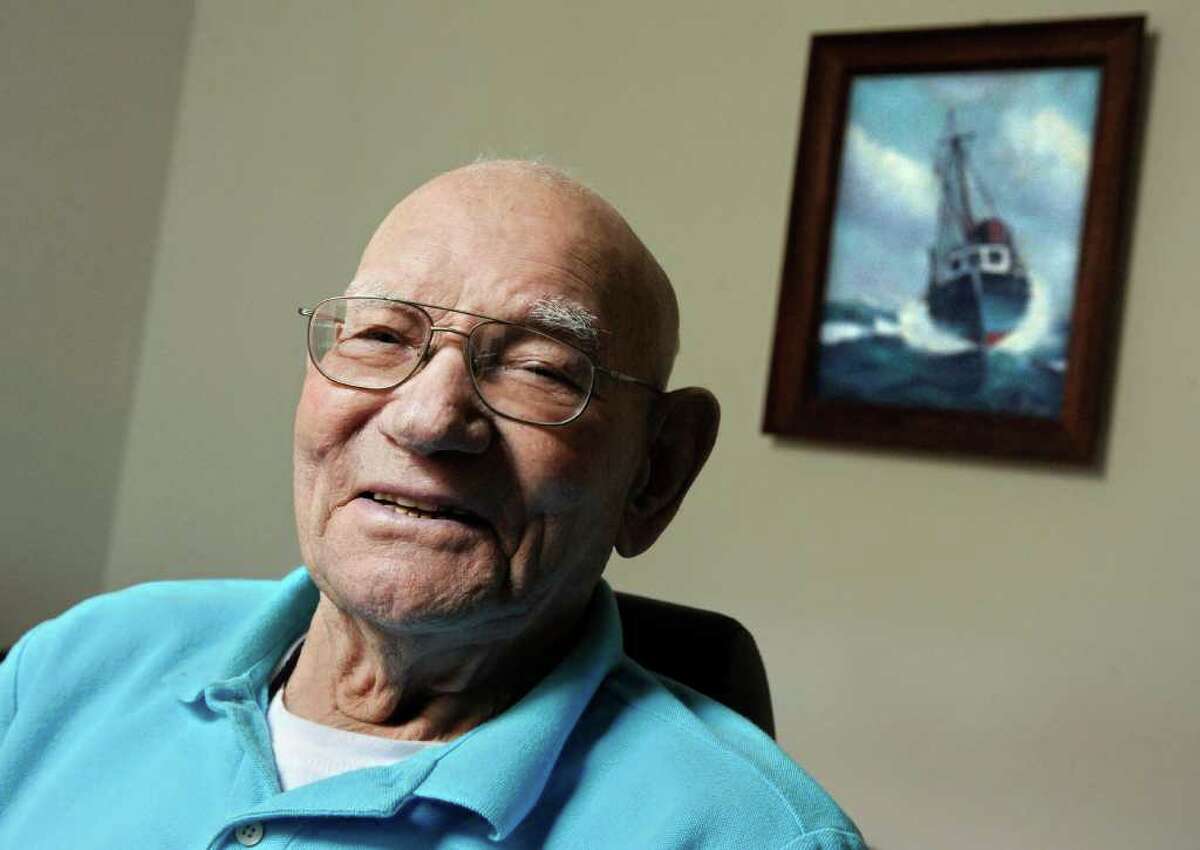 James Arruda Henry poses for a photograph with a painting of one his boats, "Little Chief", behind him at his apartment in Mystic, Conn., Wednesday, March 28, 2012. The 98-year-old retired lobsterman published his autobiographical essays after learning to read and write in his 90s. (AP Photo/Jessica Hill)