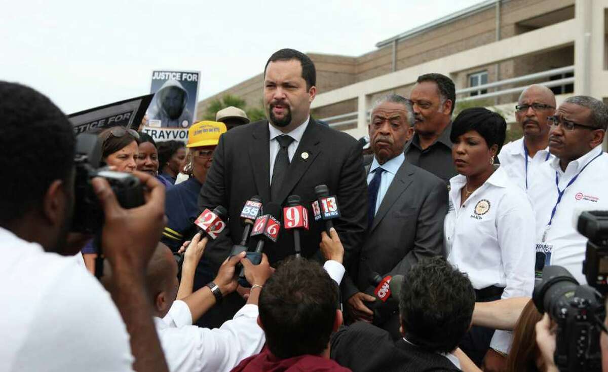 Benjamin Jealous, President of the NAACP talks to the media as Rev. Al Sharpton and Rev. Jessie Jackson, back, listens before the march and rally for slain Florida teenager Trayvon Martin on Saturday, March 31, 2012 in Sanford, Fla. Protesters carried signs, chanted ?Justice for Trayvon,? and clutched the hands of their children while they walked from Crooms Academy of Information Technology, the county?s first high school for black students, to the Sanford Police Department. The march was organized by the NAACP and was one of several taking place over the weekend. Martin was shot to death by 28-year-old George Zimmerman on Feb. 26 as he walked from back from a convenience store to his father?s fiancée?s home in a gated community outside Orlando. (AP Photo/Julie Fletcher)