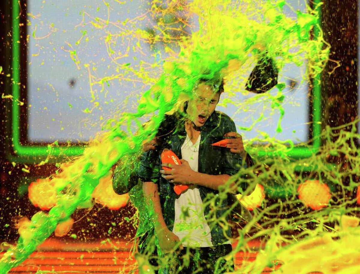 Justin Bieber loses his cap and holds onto his Blimp trophy while getting slimed after accepting the award for favorite male singer Saturday at Nickelodeon's 25th Annual Kids' Choice Awards.