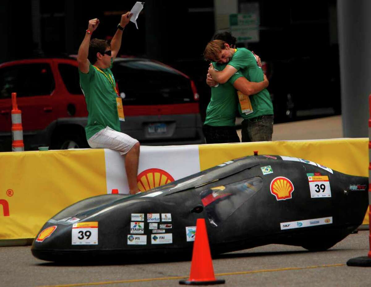 Felipe Arce Boiarski throws hands in the air as Vitor Trentini Neto embraces Andre William Tonatto, of Brazil's Unioeste-Universidade Estadual Do Oeste Do Parana, as their driver arrives to the pit upon completing laps during the Shell Eco-Marathon Americas 2012 on Sunday, April 1, 2012, in Houston. High school, university, and college students test vehicles they have designed and built to see which can go the farthest distance using the least amount of fuel.