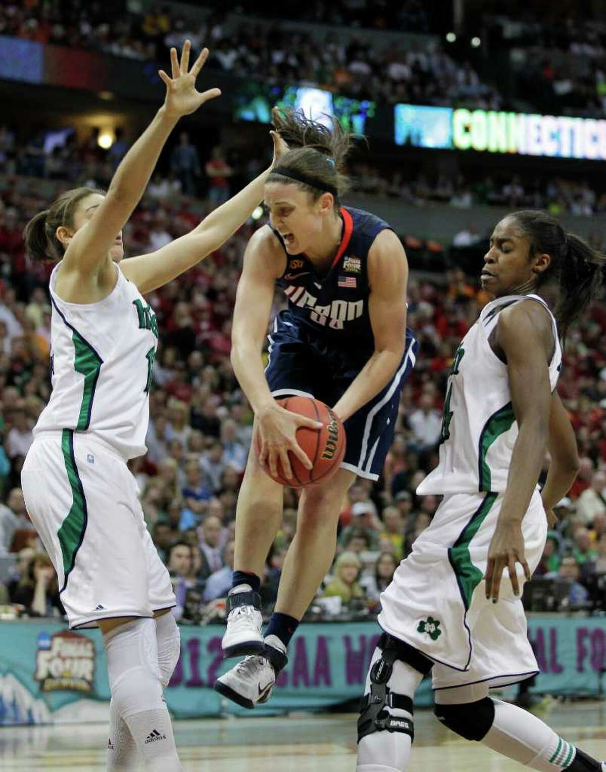 Connecticut guard Kelly Faris (34) passes between Notre Dame forward Natalie Achonwa (11) and Notre Dame forward Devereaux Peters (14) during overtime in the NCAA women's Final Four semifinal college basketball game, in Denver, Sunday, April 1, 2012. Notre Dame won 83-75. (AP Photo/Julie Jacobson)