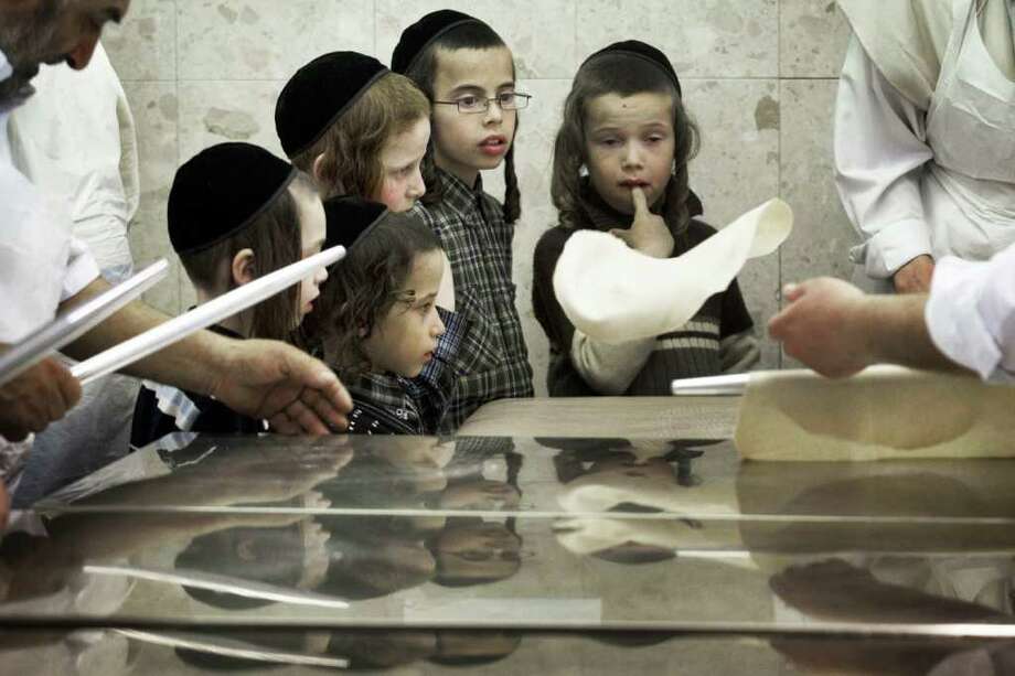 Children look on as Ultra-Orthodox Jewish men knead the dough before baking the Matzoth or unleavened bread on April 2, 2012 in Jerusalem. Religious Jews throughout the world eat matzoth during the eight-day Pesach holiday (Passover). Photo: MENAHEM KAHANA, AFP/Getty Images / 2012 AFP
