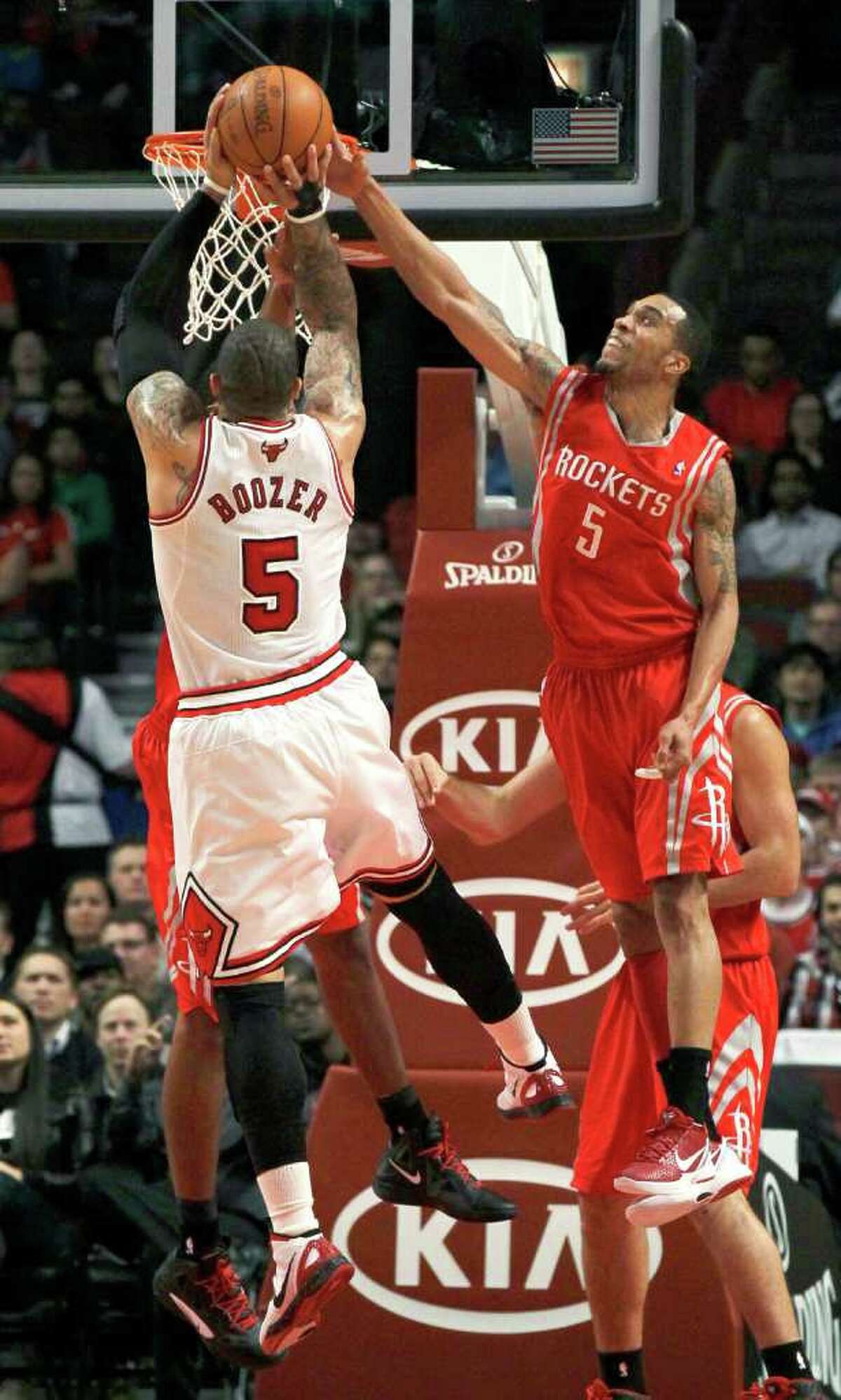 Houston Rockets guard Courtney Lee, right, blocks the shot of Chicago Bulls forward Carlos Boozer during the first half of an NBA basketball game Monday, April 2, 2012, in Chicago. (AP Photo/Charles Rex Arbogast)