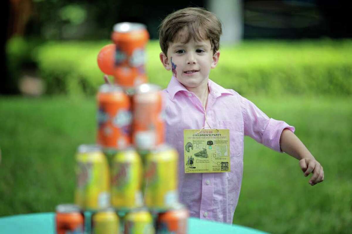 4-year-old Peter Liuzzi attempts to knock down a tower of cans during the Bayou Bend children's party.