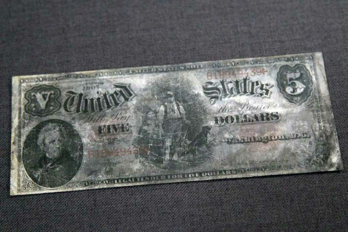 A five dollar bank note, series 1907, from the RMS Titanic Inc. is on display at Guernsey's Auctioneers & Brokers, Wednesday, April 4, 2012 in New York. The auction of more than 5,000 Titanic artifacts a century after the luxury liner's sinking has stirred hundreds of interested calls, with some offering to add to the dazzling trove already plucked from the ocean floor.