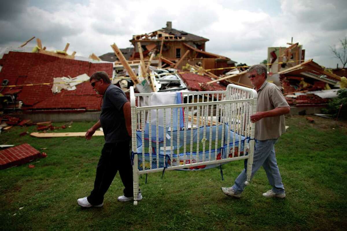 Mike Enochs (L) and Gary Enochs (R) salvage a baby crib from Mike Enochs' destroyed home after a tornado on April 4, 2012 in Forney, Texas. Multiple tornadoes touched down yesterday across the Dallas/Fort Worth area causing extensive damage.