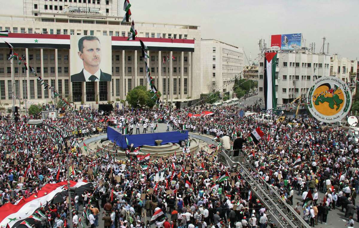 Pro-Syrian government demonstrators hold a Saturday rally in Damascus' Sabe Bahrat Square to commemorate the 65th anniversary of the foundation of the Ruling Baath Arab Socialist Party in Syria.
