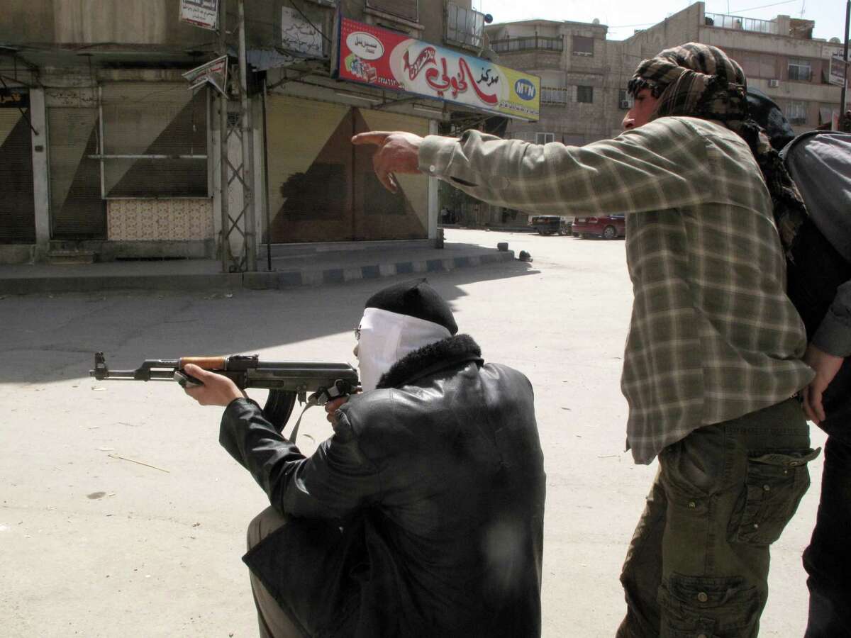 In this Friday, April 6, 2012 photo, Free Syrian Army fighters try to spot a sniper during fighting with Syrian troops in a suburb of Damascus, Syria. Syrian government shelling and offensives against rebel-held towns killed dozens of people across the country on Saturday, activists said, as the U.S. posted online satellite images of troop deployments that cast further doubt on whether the regime intends to comply with an internationally sponsored peace plan. (AP Photo)
